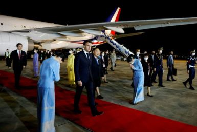 French President Emmanuel Macron (C) is greeted by Thai officials after landing in Bangkok Wednesday night for the APEC summit