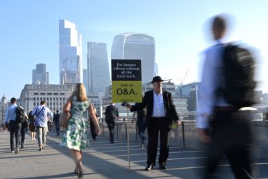 Workers walk towards the City of London financial district as they cross London Bridge during the morning rush hour in London