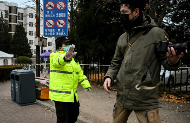 A security guard stops a journalist from taking pictures in front of the entrance gate of Tsinghua University in Beijing