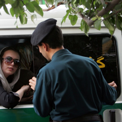 An Iranian officer (R) speaks with a woman arrested for wearing 'inappropriate' clothes in Tehran, on 23 July 2007