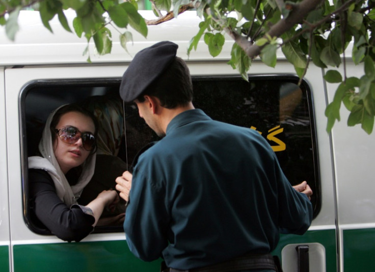 An Iranian officer (R) speaks with a woman arrested for wearing 'inappropriate' clothes in Tehran, on 23 July 2007