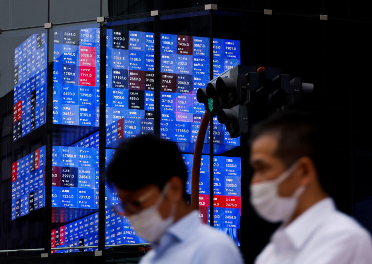 People pass by an electronic screen showing Japan's Nikkei share price index inside a conference hall  in Tokyo