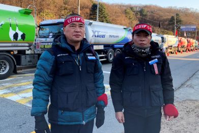 Striking South Korean unionised tank drivers Lee Geum-sang and Ham Sang-jun pose in front of tank trucks as they participate in a nationwide walkout in front of a major oil storage facility in Seongnam