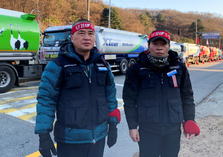 Striking South Korean unionised tank drivers Lee Geum-sang and Ham Sang-jun pose in front of tank trucks as they participate in a nationwide walkout in front of a major oil storage facility in Seongnam