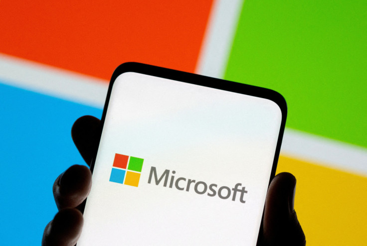 Smartphone is seen in front of Microsoft logo displayed in this illustration taken