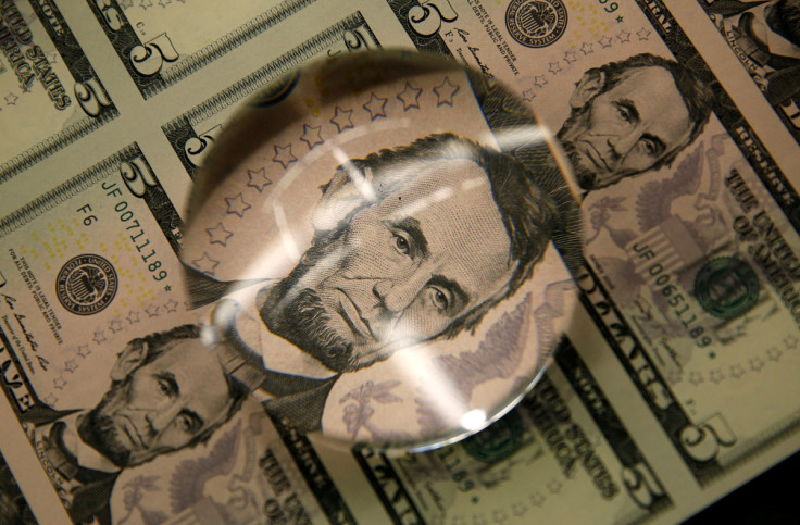 Sheets of Lincoln five dollar bills are seen through magnifying glass