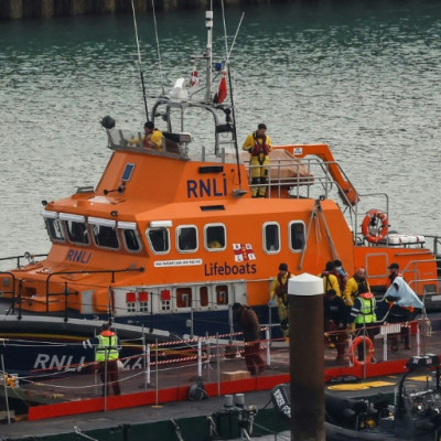 Migrants picked up at sea while attempting to cross the English Channel, are escorted off from the UK Royal National Lifeboat Institution (RNLI) lifeboat at the Marina in Dover, southeast England, on December 14, 2022.