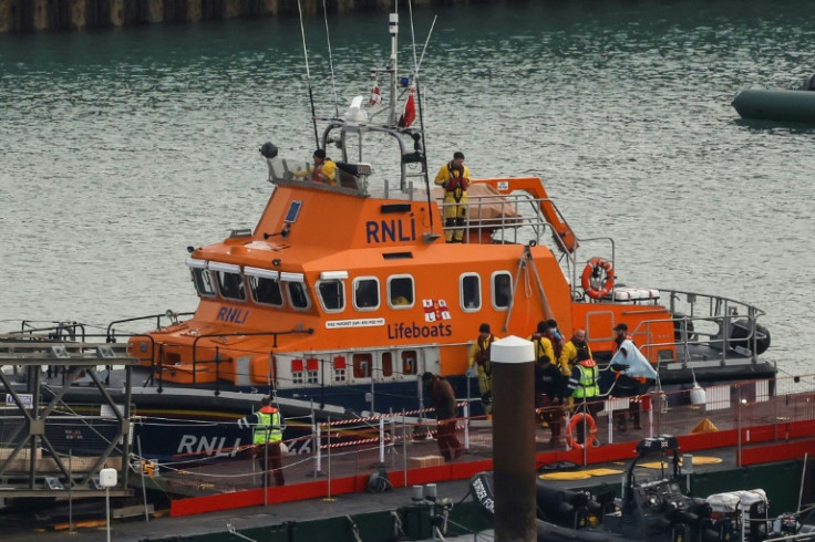 Migrants picked up at sea while attempting to cross the English Channel, are escorted off from the UK Royal National Lifeboat Institution (RNLI) lifeboat at the Marina in Dover, southeast England, on December 14, 2022.