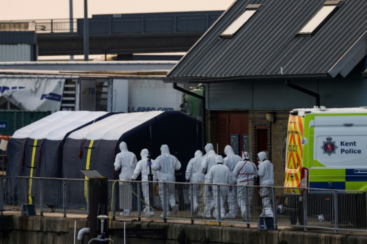 Forensics police officers arrive at the marina in Dover, southeast England, on December 14, 2022 to inspect the bodies of migrants believed to be kept inside a tent (L) outside the UK Royal National Lifeboat Institution (RNLI) office after they died overn