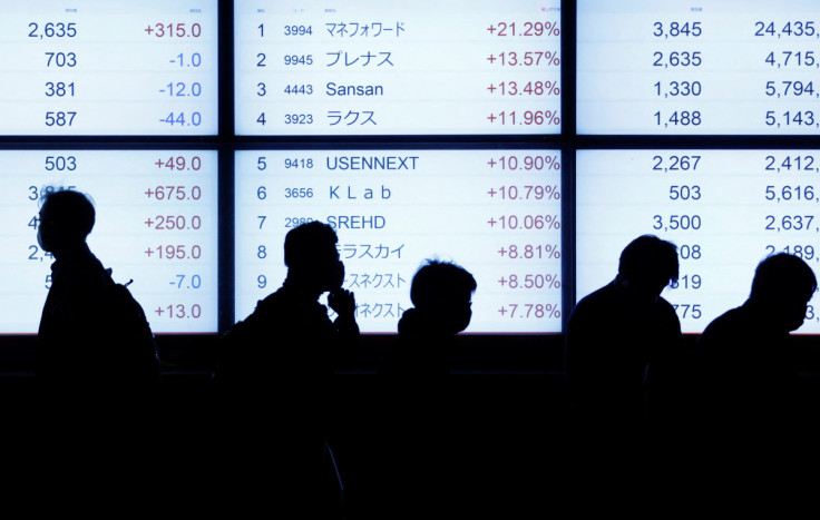 Passersby walk past in front of an electric stock quotation board outside a brokerage in Tokyo