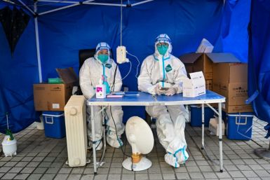 Health workers wait for people to scan a health code to test for the Covid-19 coronavirus in the Jing'an district in Shanghai on December 22, 2022.