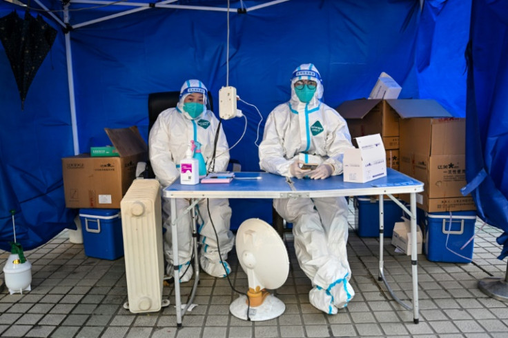 Health workers wait for people to scan a health code to test for the Covid-19 coronavirus in the Jing'an district in Shanghai on December 22, 2022.