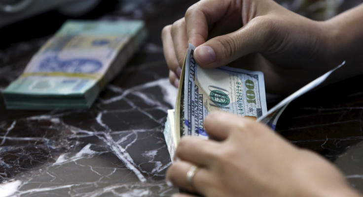 An employee counts U.S. dollar bank-notes near Vietnamese dong bank-notes at a bank in Hanoi, Vietnam