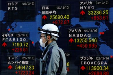 A man wearing a protective mask, amid the coronavirus disease (COVID-19) outbreak, walks past an electronic board displaying various countries' stock indexes including  Russian Trading System (RTS) Index which is empty, outside a brokerage in Tokyo