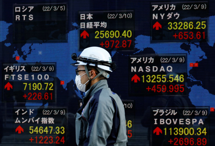 A man wearing a protective mask, amid the coronavirus disease (COVID-19) outbreak, walks past an electronic board displaying various countries' stock indexes including  Russian Trading System (RTS) Index which is empty, outside a brokerage in Tokyo