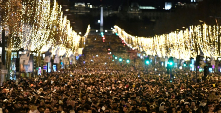 People gather on the Champs-Elysees as they wait for the New Year's Eve fireworks in Paris on December 31, 2022