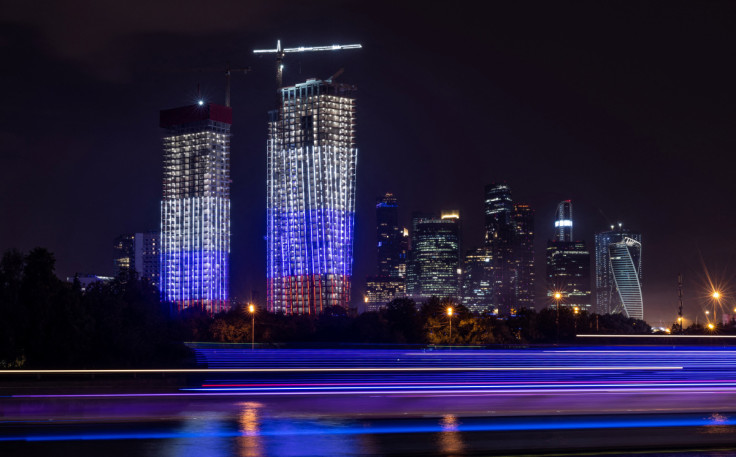 A high-rise apartment block under construction illuminated in colours of Russian flag is seen next to skyscrapers of Moscow International Business Centre in Moscow