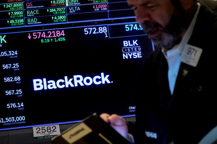 A trader works as a screen displays the trading information for BlackRock on the floor of the NYSE in New York