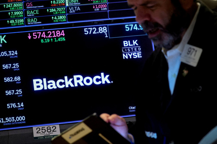 A trader works as a screen displays the trading information for BlackRock on the floor of the NYSE in New York