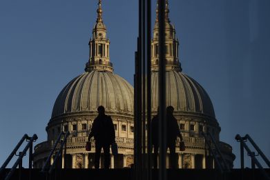 A worker descends steps near the Millenium Bridge, with St. Paul's Cathedral seen behind during the morning rush hour in the City of London