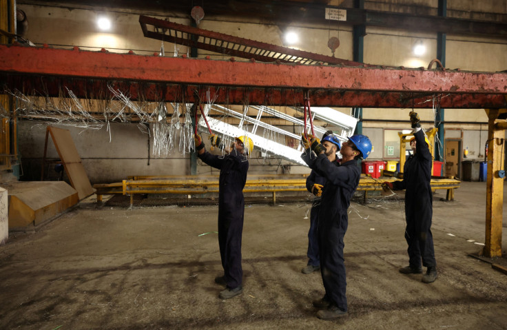 Workers remove pieces of wire from a frame inside the factory of Corbetts The Galvanizers in Telford