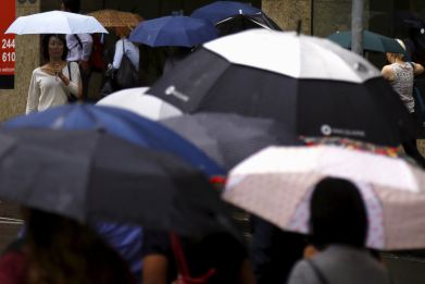 Pedestrians hold umbrellas as they walk to office buildings on a rainy morning in central Sydney, Australia