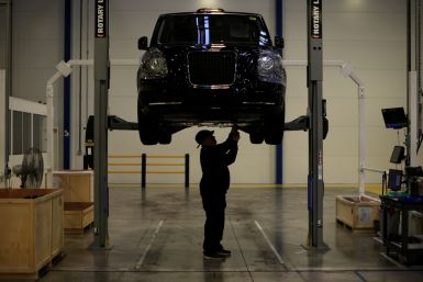 A worker stands beneath a TX electric taxi inside the LEVC (London Electric Vehicle Company) factory in Coventry