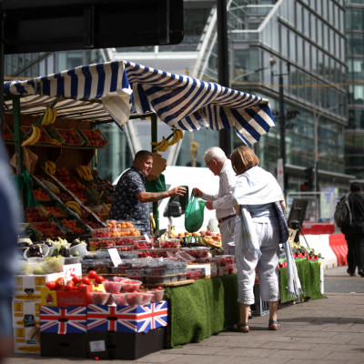 A person buys produce from a fruit and vegetable market stall in central London