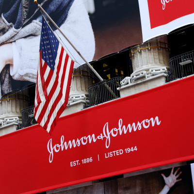 The U.S. flag is seen over the company logo for Johnson & Johnson to celebrate the 75th anniversary of the company's listing at the NYSE in New York