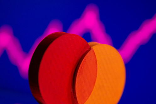 A 3D printed Mastercard logo is seen in front of displayed stock graph in this illustration