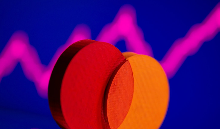 A 3D printed Mastercard logo is seen in front of displayed stock graph in this illustration