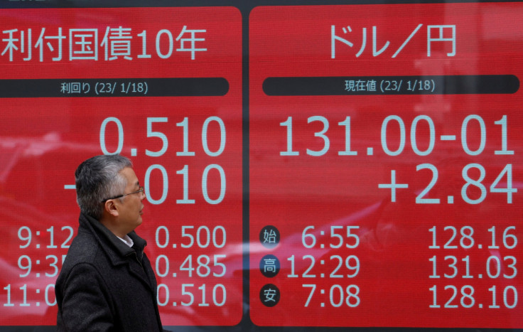 A man looks at electric monitors displaying Japan's 10-year government bond yield on gilts and the exchange rate between the Japanese yen against the U.S. dollar outside a brokerage in Tokyo