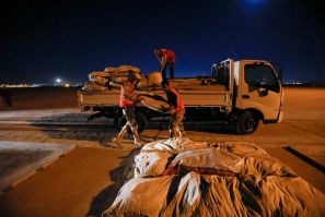 Iraqi soldiers and Iraqi Red Crescent society workers unload trucks with aid that will be shipped on a plane of emergency relief to Syria, in Baghdad