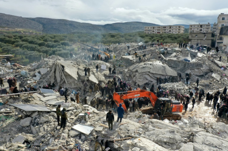 Residents search for victims and survivors amidst the rubble of collapsed buildings in the Syrian village of Besnia
