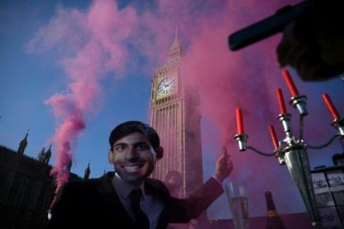 An activist wears a mask depicting Britain's Prime Minster Rishi Sunak during a protest by animal and climate justice group Animal Rebellion