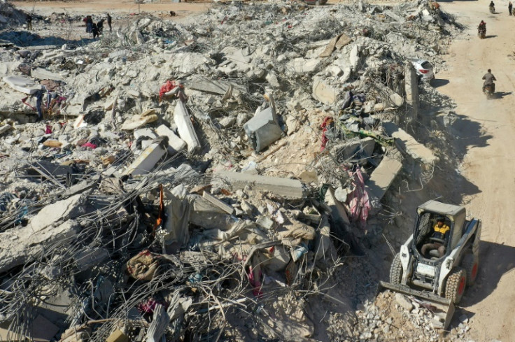 A tractor works to move rubble from a collapsed building in the Syrian rebel-held town of Jindayris