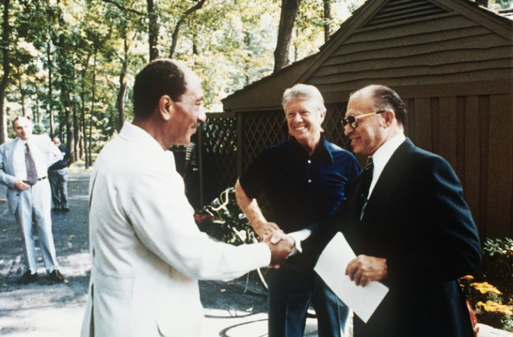 Egyptian president Anwar al-Sadat (L) shakes hands with Israeli premier Menachem Begin, as US president Jimmy Carter looks on at Camp David, in September 1978