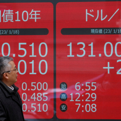 A man looks at electric monitors displaying Japan's 10-year government bond yield on gilts and the exchange rate between the Japanese yen against the U.S. dollar outside a brokerage in Tokyo