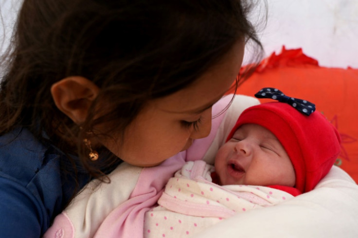 Khalil al-Suwadi's daughters gathered around the baby, embracing and kissing her