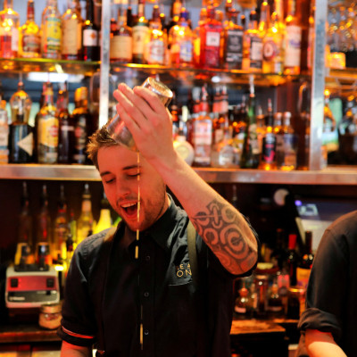 A bartender makes cocktails in a bar in central London