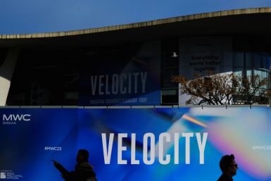 Workers walk past a billboard of GSMA's 2023 ahead of the Mobile World Congress (MWC) in Barcelona