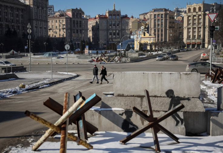 People walk down a street near anti-tank constructions in central Kyiv