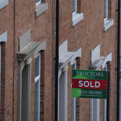 An estate agent's board is displayed outside a house on a terraced street in Blackburn