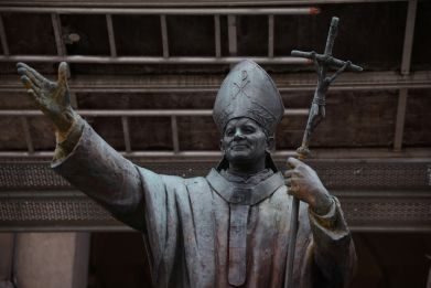 Pope John Paul II statue stands in front of a church in Warsaw