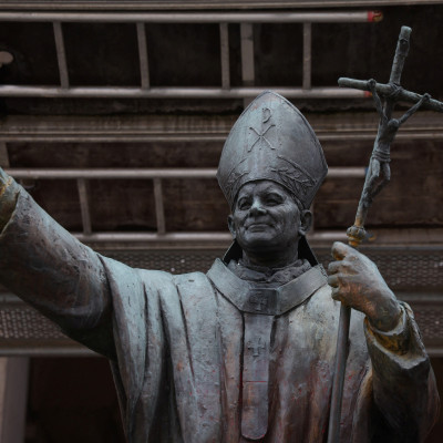 Pope John Paul II statue stands in front of a church in Warsaw