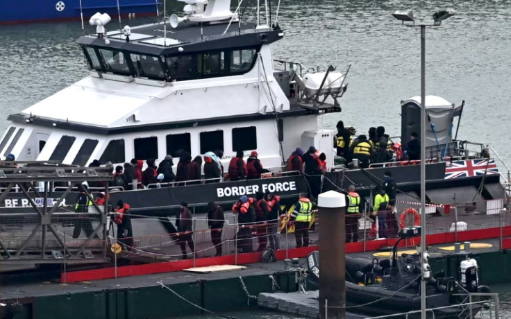 Migrants are escorted ashore from a UK Border Force vessel in Dover after being picked up at sea