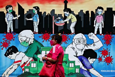 A woman wearing a protective face mask walks past a mural promoting awareness of the coronavirus disease (COVID-19) outbreak, in Jakarta
