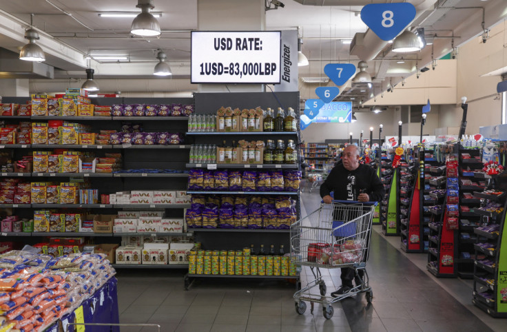 A man pushes a shopping cart near a screen showing the exchange rate of Lebanese pound to U.S. dollars inside a supermarket in Beirut