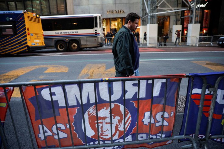 A man walks on Fifth Avenue as a campaign flag of former U.S. President Donald Trump hangs on a barricade in front of Trump Tower in midtown Manhattan in New York City