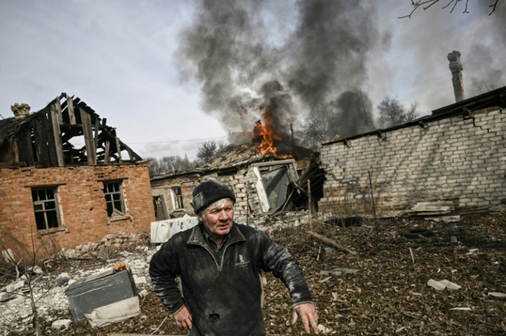 A man stands outside a burning house after shelling in the town of Chasiv Yar, near Bakhmut